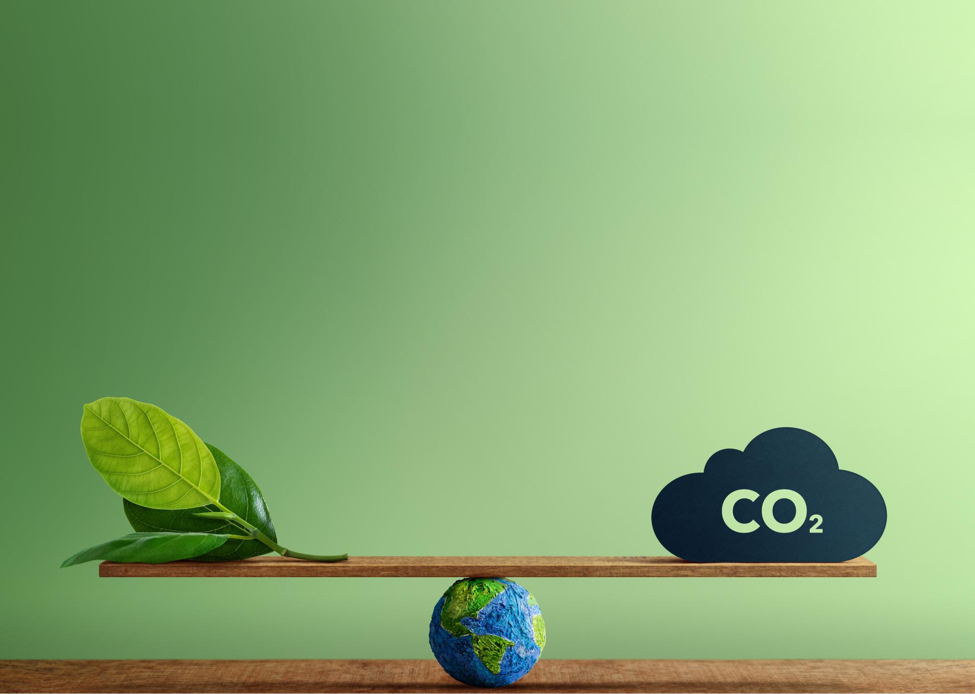 CO2 Neutral und saubere Energie: Globe Balancing zwischen einem grünen Blatt und CO2.